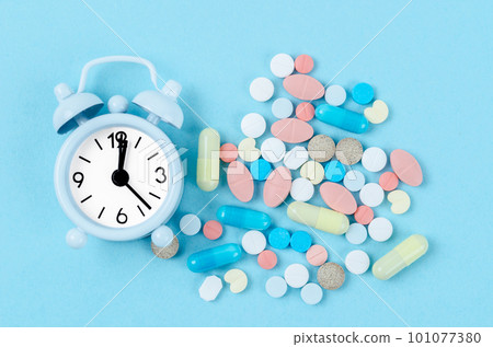 The pills and alarm clock on blue background The pills and alarm clock on blue background 101077380