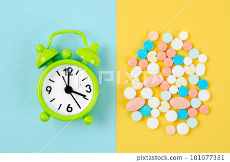 The pills and alarm clock on the blue and yellow color background The pills and alarm clock on the blue and yellow color background 101077381