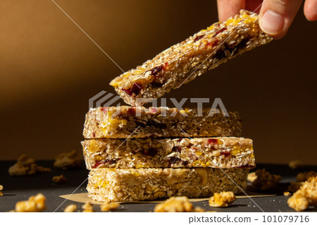Woman takes Homemade Granola energy bar. Variety of protein granola breakfast bars, with nuts, raisins dried cherries and chocolate. Healthy nutrition eating Gluten free cereal dieting snack super Woman takes Homemade Granola energy bar. Variety of protein granola breakfast bars, with nuts, raisins dried cherries and chocolate. Healthy nutrition eating Gluten free cereal dieting snack super 101079716