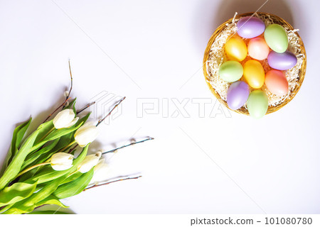 Colorful Easter eggs in a basket. Bouquet of tulips and willow branches. Congratulatory background. Colorful Easter eggs in a basket. Bouquet of tulips and willow branches. Congratulatory background. 101080780
