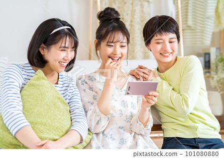 一個年輕的女人，看著她的智能手機上的視頻 101080880