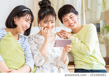 一個年輕的女人,看著她的智能手機上的視頻 一個年輕的女人,看著她的智能手機上的視頻 101080881