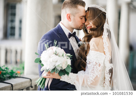 Beautiful young wedding couple posing with bouquet of flowers in hands 101081530