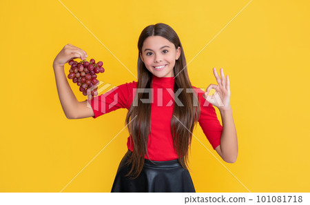teen kid smile hold bunch of grapes on yellow background 101081718