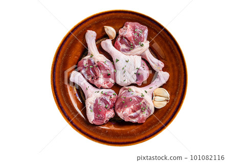 Raw Poultry meat - Duck legs drumsticks on a rustic plate with herbs. Isolated on white background. 101082116