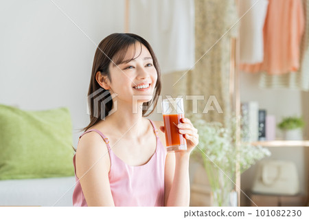 Young woman drinking vegetable juice in the living room Young woman drinking vegetable juice in the living room 101082230