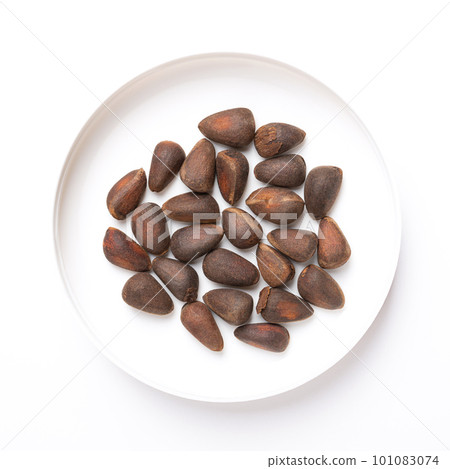 Seeds of a stone pine, in a white plastic lid, from above. Nuts from a cone of Pinus cembra, also known as Swiss, Arolla or Austrian stone pine, a European white pine tree in the subgenus Strobus. 101083074