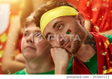 Bored male face. Sport fans emotionally cheering up favourite football, soccer team of portugal at stadium during game 101083111
