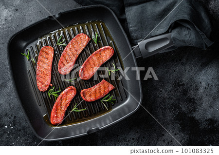 Fried Turkish Sucuk meat sausage on a grill skillet. Black background. Top view 101083325