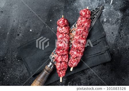 Raw kofta, kofte kebab Skewers with beef and lamb meat and spices. Black background. Top view 101083326