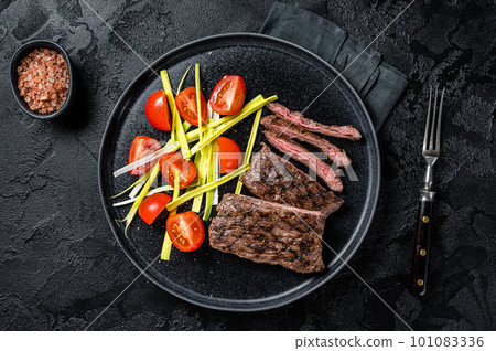 Grilled arrachera Skirt steak with garnish. Black background. Top view Grilled arrachera Skirt steak with garnish. Black background. Top view 101083336