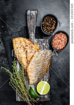 Roast Gilthead Sea Bream fillets with herbs on wooden board. Black background. Top view 101083385