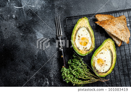 Cooking Baked Avocado with Egg. Black background. Top view. Copy space Cooking Baked Avocado with Egg. Black background. Top view. Copy space 101083419
