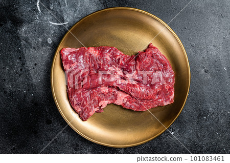 Alternative choice steak - Skirt or Machete, raw beef meat. Black background. Top view Alternative choice steak - Skirt or Machete, raw beef meat. Black background. Top view 101083461
