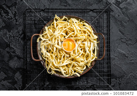 Dry spaetzle egg noodle in a steel tray. Black background. Top view 101083472