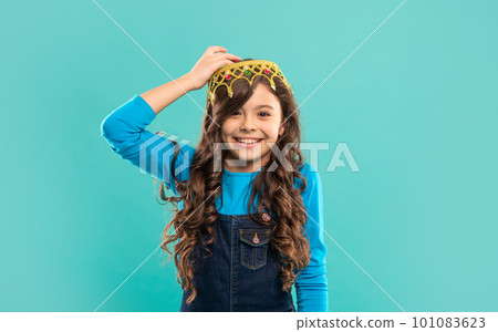 cheerful child with curly hair in queen crown on blue background, egoist cheerful child with curly hair in queen crown on blue background, egoist 101083623