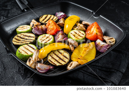 Vegetables grilled in a grill skillet, bell pepper, zucchini, eggplant, onion and tomato. Black background. Top view 101083640
