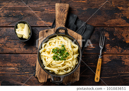German Spaetzle egg Noodles with Butter and Parsley in a skillet. Wooden background. Top view German Spaetzle egg Noodles with Butter and Parsley in a skillet. Wooden background. Top view 101083651