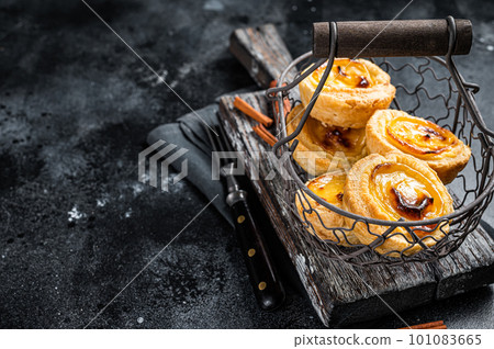 Traditional Lisbon Pasteis de nata in a basket. Black background. Top view. Copy space 101083665