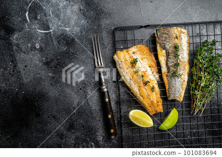 Grilled sea bass fillet with lime and thyme. Black background. Top view. Copy space 101083694