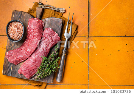 Butcher table with Raw lamb tenderloin Fillet, Mutton loin Meat with thyme. Orange background. Top view. Copy space Butcher table with Raw lamb tenderloin Fillet, Mutton loin Meat with thyme. Orange background. Top view. Copy space 101083726