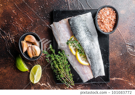 Sea Bass fillets, Raw Seabass fish with thyme, pink salt and lemon on marble board. Dark background. Top view Sea Bass fillets, Raw Seabass fish with thyme, pink salt and lemon on marble board. Dark background. Top view 101083772