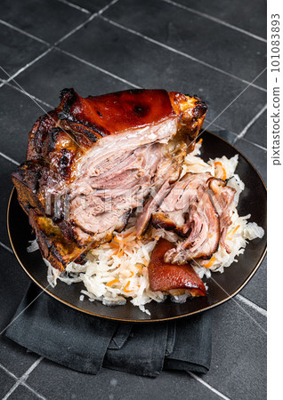 Roast Pork Ham Hock, knuckle with Sauerkraut on a plate. Black background. Top view 101083893