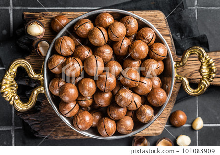Macadamia nuts in a shell ready to eat. Black background. Top view 101083909