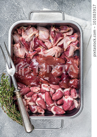 Raw chicken offals meat set, gizzards, stomachs, liver and hearts in a steel tray with herbs. White background. Top view Raw chicken offals meat set, gizzards, stomachs, liver and hearts in a steel tray with herbs. White background. Top view 101083917