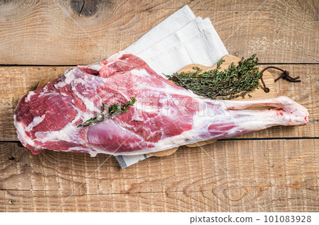 Butcher board with Raw lamb mutton leg with herbs. Wooden background. Top view Butcher board with Raw lamb mutton leg with herbs. Wooden background. Top view 101083928