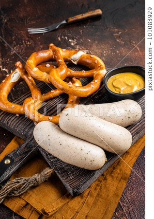 Traditional German pretzel with white sausage and mustard. Dark background. Top view 101083929