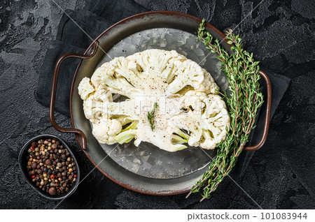 Vegetarian cuisine - cooking of cauliflower steak. Black background. Top view Vegetarian cuisine - cooking of cauliflower steak. Black background. Top view 101083944