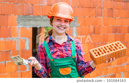 Architecture construction child. Child in uniform working around brick wall. labour day concept. Little girl bricklayer. learning how to build. Little worker in helmet building. Repairman in uniform Architecture construction child. Child in uniform working around brick wall. labour day concept. Little girl bricklayer. learning how to build. Little worker in helmet building. Repairman in uniform 101084163