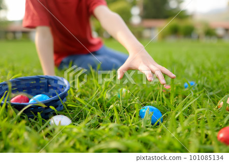 Little boy hunting for eggs in spring garden on Easter day. Traditional festival outdoors. Child celebrate Easter holiday. Focus on hand. 101085134