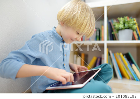 Preschooler boy watches cartoon movie by tablet or playing pc game. Overuse and addiction kids from gadgets. 101085192
