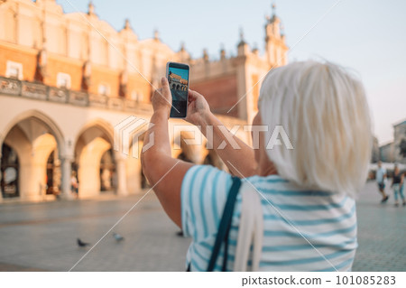 Beautiful Krakow market square, Poland, Europe. A hand taking photo of Sukiennice with smartphone, Krakow, Poland 101085283