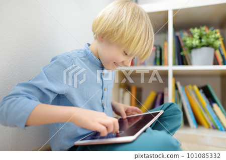 Preschooler boy watches cartoon movie by tablet or playing pc game. Overuse and addiction kids from gadgets. 101085332