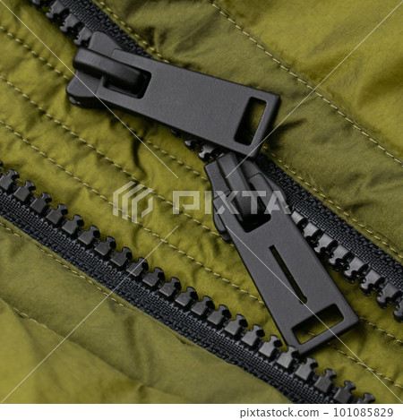 Double black matte zipper on bright green jacket. Close up 101085829