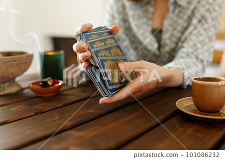 Fortune teller with tarot cards on table near burning candle.Tarot cards spread on table with magic herbs and palo santo aroma sticks. Forecasting concept Fortune teller with tarot cards on table near burning candle.Tarot cards spread on table with magic herbs and palo santo aroma sticks. Forecasting concept 101086232
