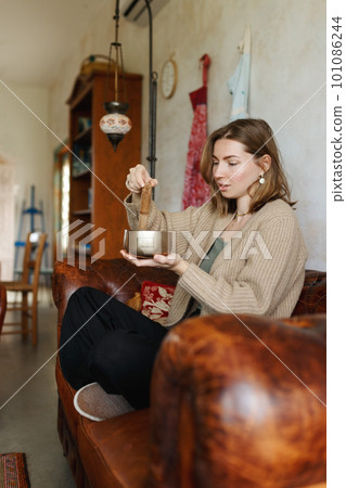 Young woman playing on a singing tibetian bowl.Relaxation and meditation.Sound therapy,alternative medicine.Buddhist healing practices.Clearing space of negative energy.Selective focus,close up. Young woman playing on a singing tibetian bowl.Relaxation and meditation.Sound therapy,alternative medicine.Buddhist healing practices.Clearing space of negative energy.Selective focus,close up. 101086244