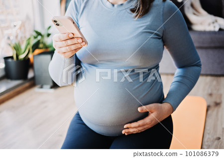 Pregnancy Workout Apps, Pregnancy Exercise Apps. Prenatal and Postnatal Workout, Pregnancy Wellness and Yoga Workouts in cell phone. Pregnant woman looking for Workout in phone 101086379