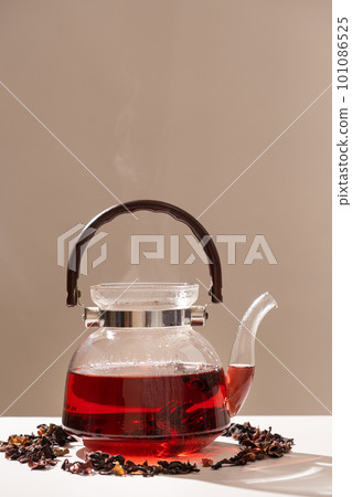 Red hibiscus tea from the petals of a Sudanese rose in a glass teapot 101086525