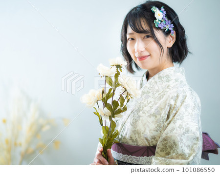 A woman holding a flower in her hand and wearing a Western-style floral pattern (kimono): white background A woman holding a flower in her hand and wearing a Western-style floral pattern (kimono): white background 101086550