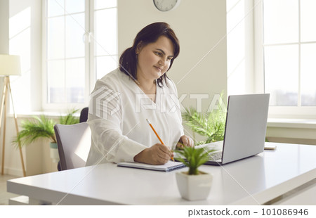 Overweight brunette young woman using laptop in modern office 101086946