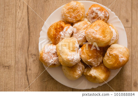 Ruddy fragrant donuts sprinkled with powdered sugar in a plate Ruddy fragrant donuts sprinkled with powdered sugar in a plate 101088884