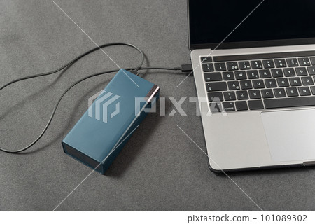 Laptop is connected by cord to an external battery. Workplace with laptop is charged by power bank Laptop is connected by cord to an external battery. Workplace with laptop is charged by power bank 101089302