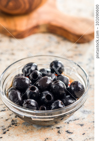 Pitted black olives in bowl on kitchen table. Pitted black olives in bowl on kitchen table. 101090600