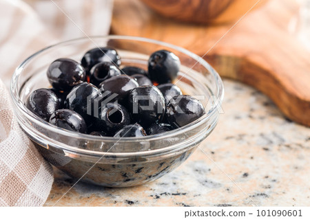 Pitted black olives in bowl on kitchen table. Pitted black olives in bowl on kitchen table. 101090601
