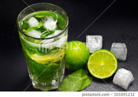 Mojito cocktail with ice, fresh mint and lime on a dark background, close-up.  101091232