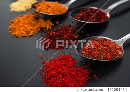 Spoons with seasonings and spices on a black background. Colorful spices in spoons 101091414